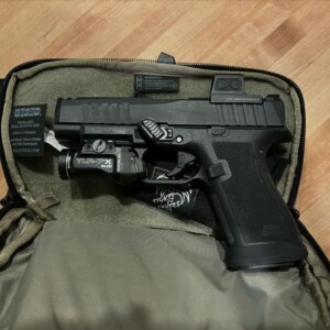 Black handgun placed inside a tactical pouch with a magazine beside it.